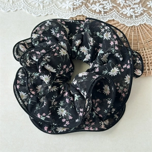 Floral print scrunchie in black sheer chiffon fabric on a rustic wicker background