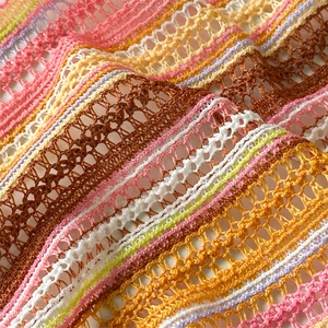 Detailed close-up of striped hollow knit fabric with colorful crochet pattern texture