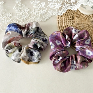 Detailed macro view of two satin scrunchies featuring Van Gogh style ink painting patterns