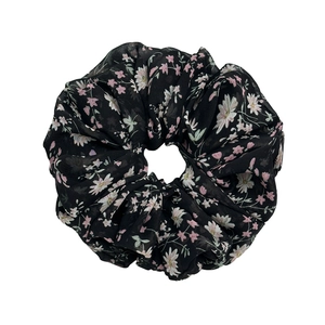 Black floral chiffon scrunchie with daisy print and ruffled edges on white background