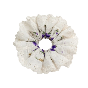 Floral scrunchie with lace edges featuring purple and yellow blossoms on beige fabric