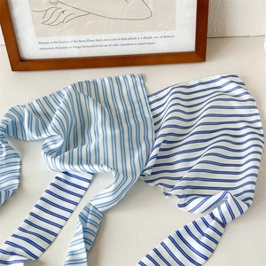 Blue and white striped fabric hair scarf and bag accessory displayed on white surface