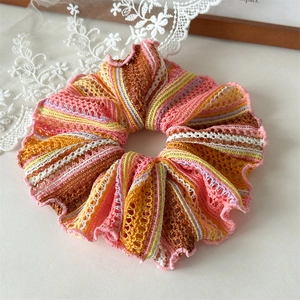 Detailed close-up of hollow knit hair scrunchie with multi-color stripes and ruffled edges