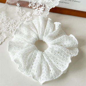 Macro shot of elegant white lace scrunchie with detailed hollow knit patterns
