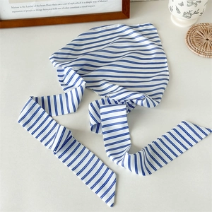 Detail of blue and white striped fabric headscarf with long ties on a stylish table