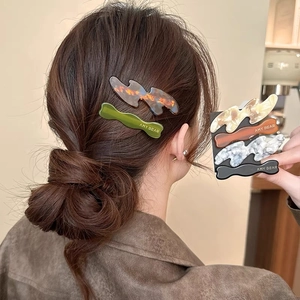 Close-up of wavy acetate hair clips in tortoiseshell and marble patterns for women