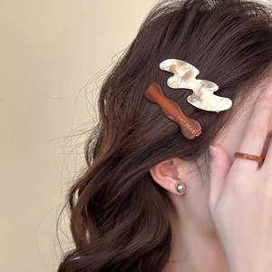 Detail view of acetate wave hair clips in marble brown and cream on hair with Amy Bear text