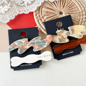 Detail view of acetate wave hair clips with marble texture and logo on display card