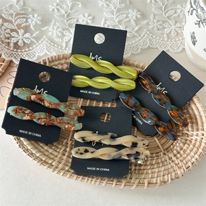 Detailed close-up of four assorted acetate hair clips on display cards in a wicker tray