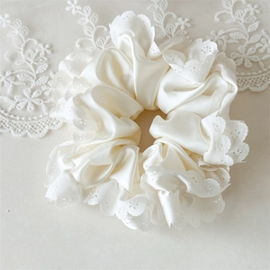 Detailansicht von cremefarbenem Satin-Haargummi mit Spitze und eleganter Seidentextur