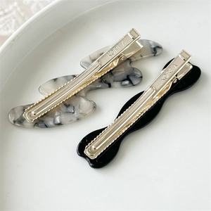 Close-up of marble acetate and black duckbill hair clips with silver metal hardware