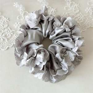 Detail von silbernem Satin-Haargummi mit weißer Spitze und lasergeschnittenen Blumen