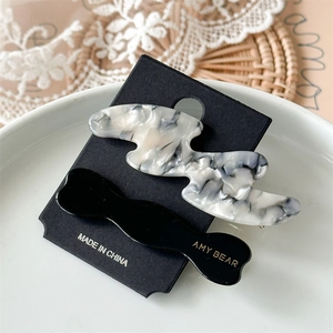 Set of marble texture acetate hair clips and black wave hairpin on elegant display