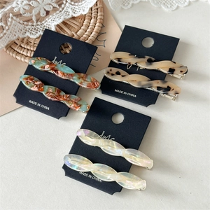 Detail of twisted acetate hair clips in marble red, leopard, and pearlescent white