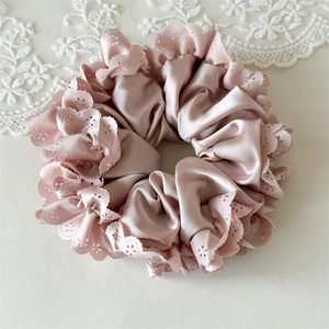 Detail von rosa Satin-Haargummi mit gewellter Lochspitze und seidiger Textur