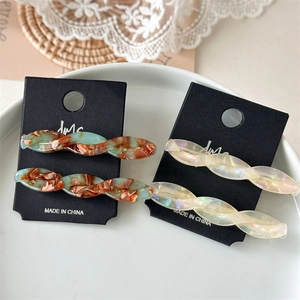 Detailed close-up of acetate twisted hair clips in marble and pearlescent white finish
