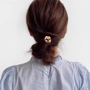 Détail d'un élastique en acétate ambré pour styliser une queue de cheval basse chic