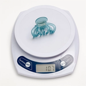 Blue acetate hair claw clip with multi-claw design on weight scale showing 10.7g mass