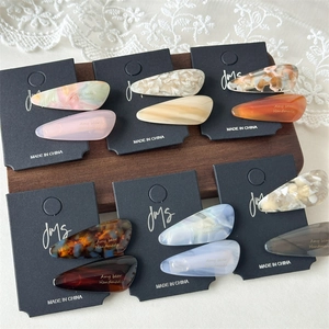 Teardrop acetate hair clips with amber and marble patterns on display card