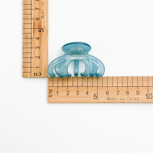 Detailed view of a blue acetate hair claw clip with France Handmade text and size ruler