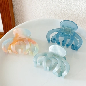 Detailed close-up of acetate hair claws in assorted colors on a marble tray