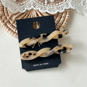 Close-up of two tortoise shell acetate twist hair clips on a display card with lace decor