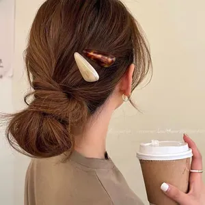 Detail showing two acetate teardrop hair clips on a model with a low bun hairstyle