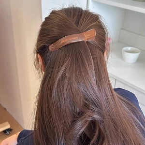 Translucent brown jelly hair clip with glitter finish securing long straight hair