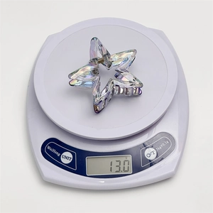 Detail showing the iridescent laser hollow star hair claw weight of 13.0g on a scale