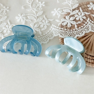 Detail of blue acetate hair claws with gold France Handmade text on lace background