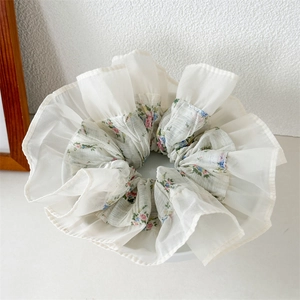 Detail of floral chiffon scrunchie with layered ruffle edges in soft pearl white