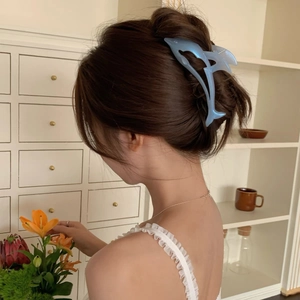 Gros plan d'une pince à cheveux dauphin bleu clair nacré dans une demi-coiffure