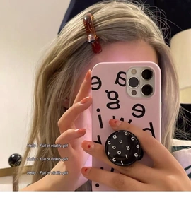 Pink iPhone case with black pop-socket and tortoise shell hair clip in mirror selfie