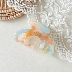 Detail of cellulose acetate hair claw clip with colorful mosaic texture on white lace