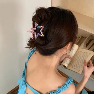 Detail of laser hollow star hair claw clip with iridescent finish on a high bun hairstyle
