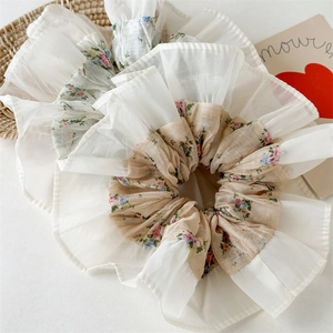 Close-up of floral scrunchies with white chiffon ruffle edges on a soft background