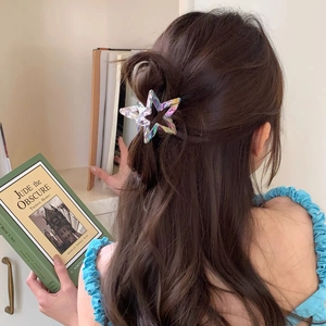 Detailed view of iridescent laser hollow star hair claw clip on model's half-tied hairstyle
