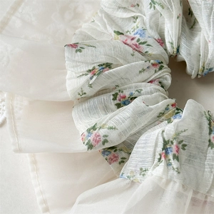 Close-up of floral scrunchie with layered ruffles and textured cream chiffon fabric