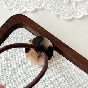 Gros plan d'un élastique avec bouton écaille et gravure France Handmade sur tissu