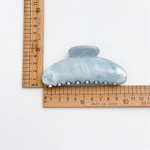 Détail d'une pince à cheveux bleue à texture d'encre mesurant 10cm par 5cm de longueur