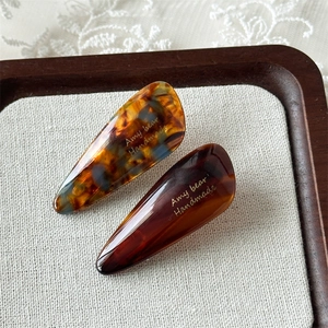 Detail of teardrop acetate hair clips with tortoiseshell pattern and gold handmade logo