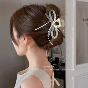 Détail d'une grande pince à cheveux en résine vert clair avec nœud blanc sur modèle