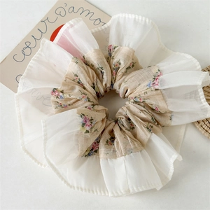 Detail of floral chiffon scrunchie with layered beige petals and sheer ruffled edges