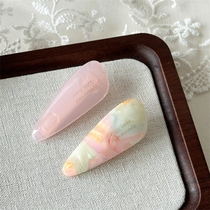 Macro shot of acetic acid teardrop hair clips with marble texture on a wooden tray