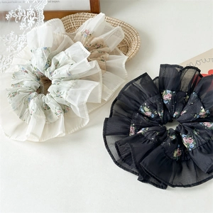 Detail of cream and black floral chiffon scrunchies with ruffled edges in a rustic layout
