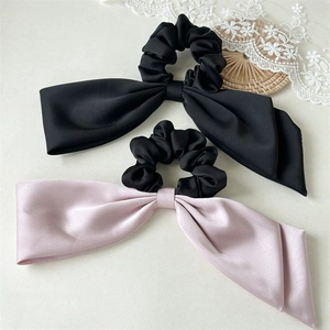 Detailed view of satin silk hair scrunchies with long double bows in black and soft pink