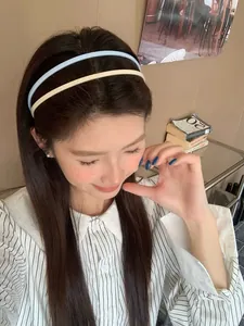 Detail of cream colored double-layer acrylic headbands worn by a model in soft light