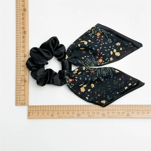 Black double satin bow scrunchie with colorful floral patterns on a white background
