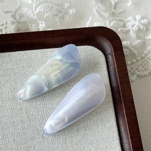 Detailed close-up of marble pattern acetate hair clips on linen fabric with lace