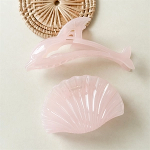Détail de pinces à cheveux rose en forme de dauphin et coquillage au fini nacré